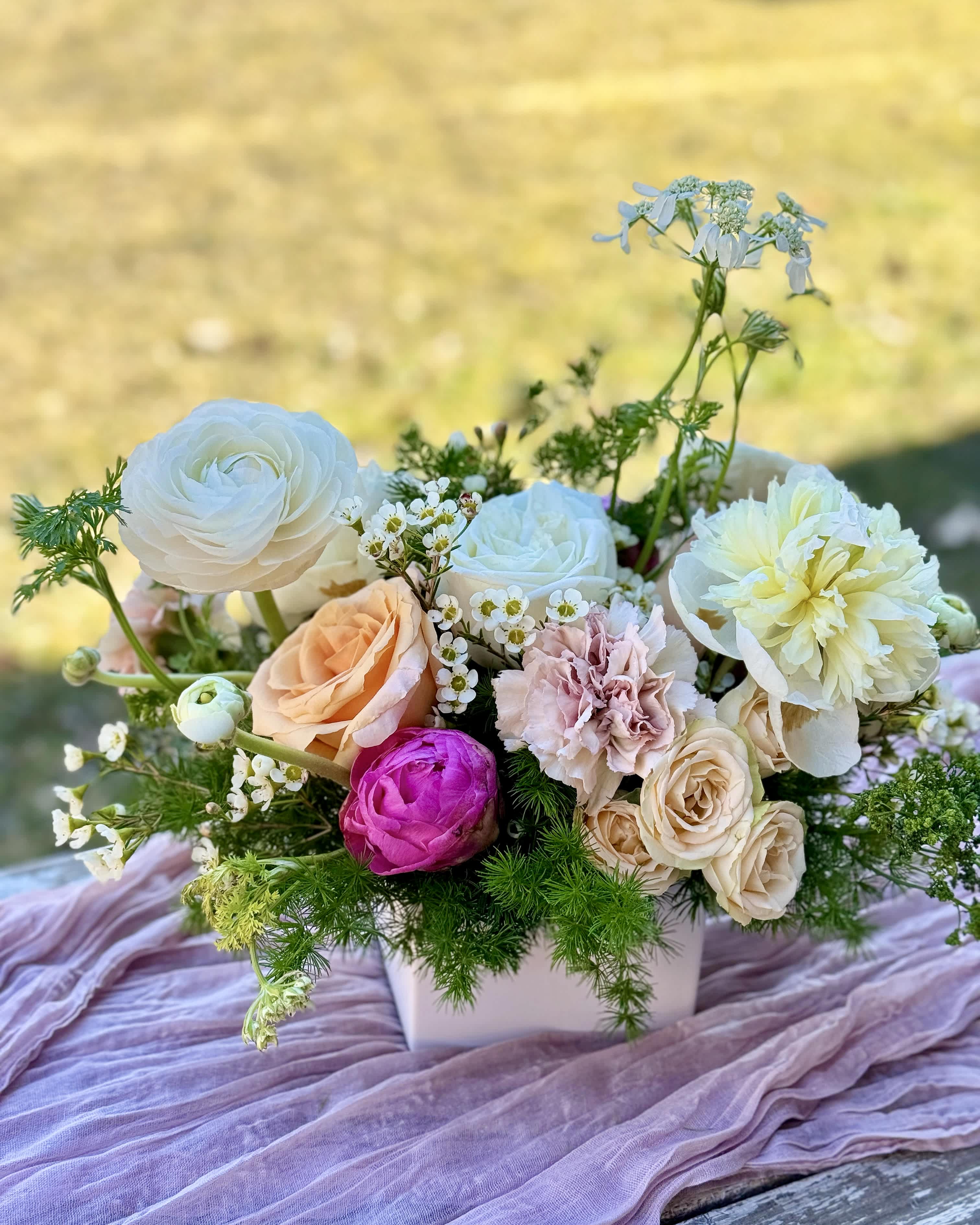 Le Jardin - An arrangement made for a beautiful tablescape. A mini rectangular dish holding an organic arrangement of fresh spring flowers in a neutral pallet with a few pops of color and greenery
