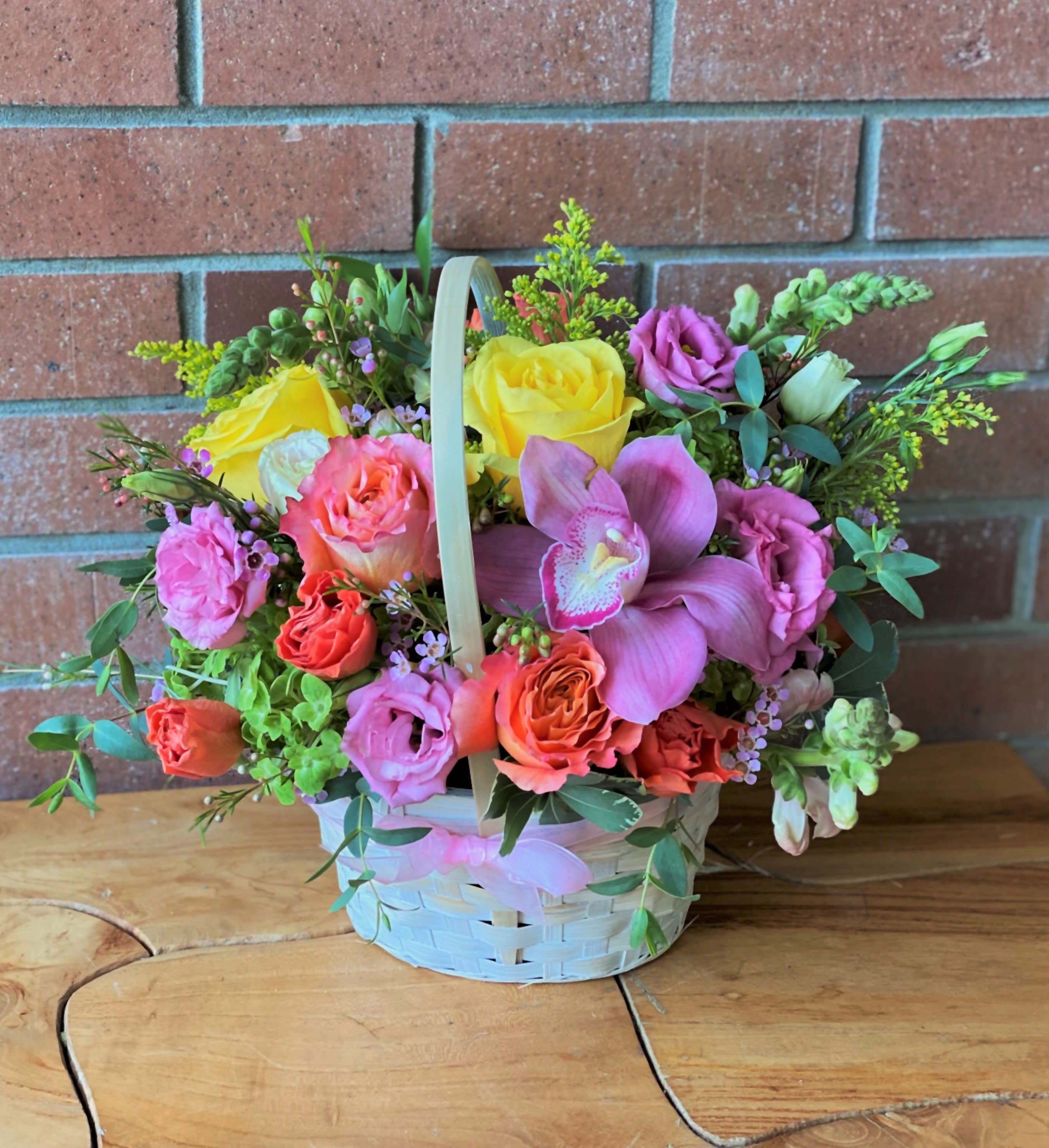 Basket Of Blooms  - Beautiful bright colored roses, spray roses, hydrangeas, orchids and lisianthus are accented with wax flowers and lush greens to create an amazing flower basket.