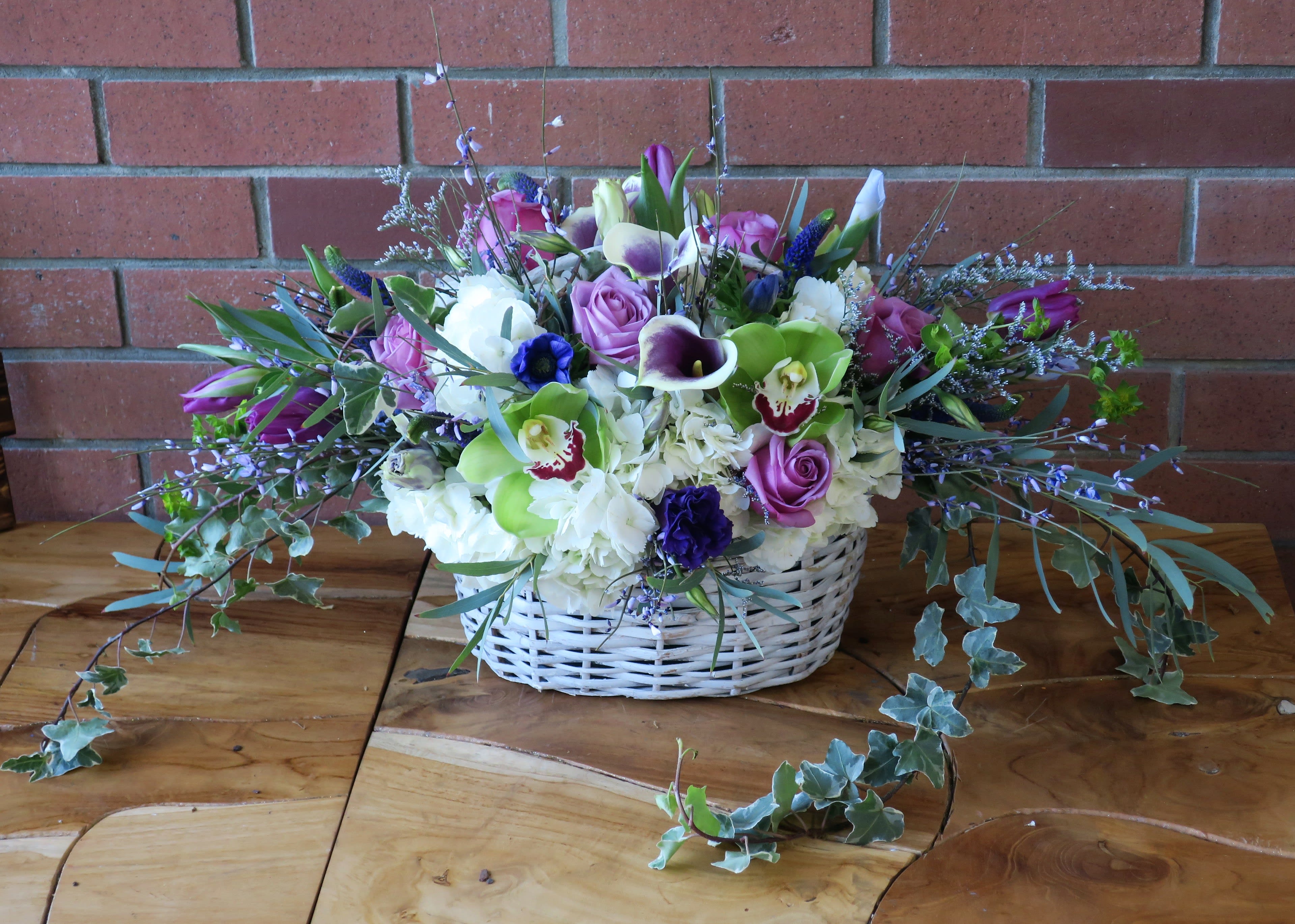 Basket Of Love - Fresh cut hydrangeas, orchids, mini calla lilies, roses, veronica, lush ivy and feather eucalyptus arranged in a beautiful white basket.