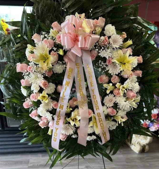 Pink &amp; white Sympathy Wreath - Medium Pink &amp; white Sympathy wreath includes Roses, carnations, lilies, daisies and filler greenery. Metal stand included*