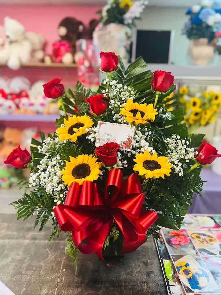 Rose and sunflower arrangement  - 7 red roses and 4 sunflowers in basket with green filler and baby breath.