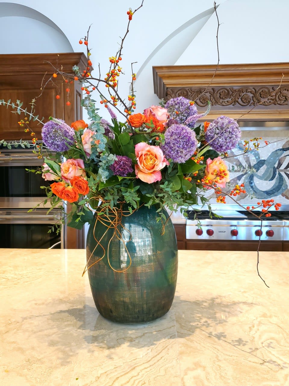 Country Lady - Send an artistic design that makes her feel like she is sitting countryside with her favorite read! This design houses a variety of country greens, alium, gorgeous purple carnation, pops of brightly colored roses in a contemporary statement piece container. 
