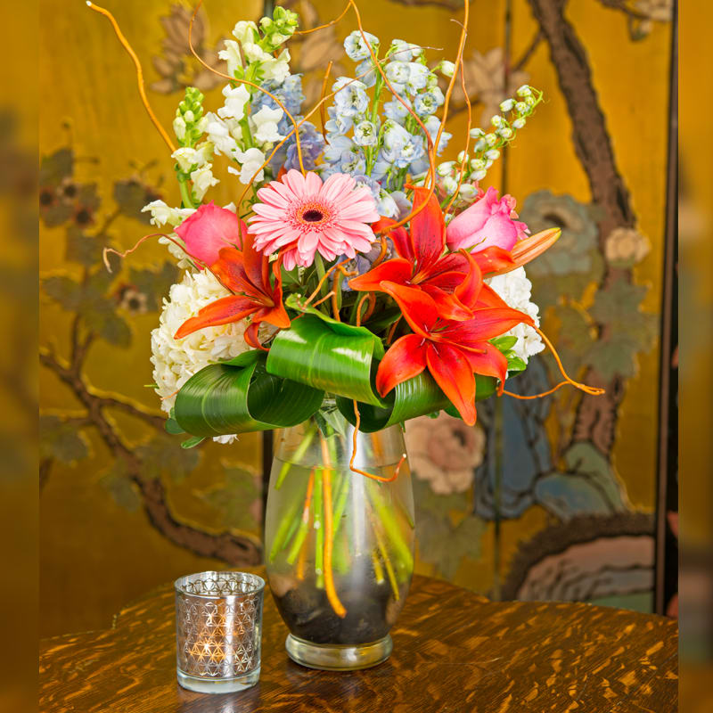 HAPPY HOLIDAY - A BEAUTIFUL ASSORTMENT OF FLOWERS,LILIES, HYDRANGEA, DELPHINIUM, WITH WRAPPED LEAVES AND CURLY WILLOW.