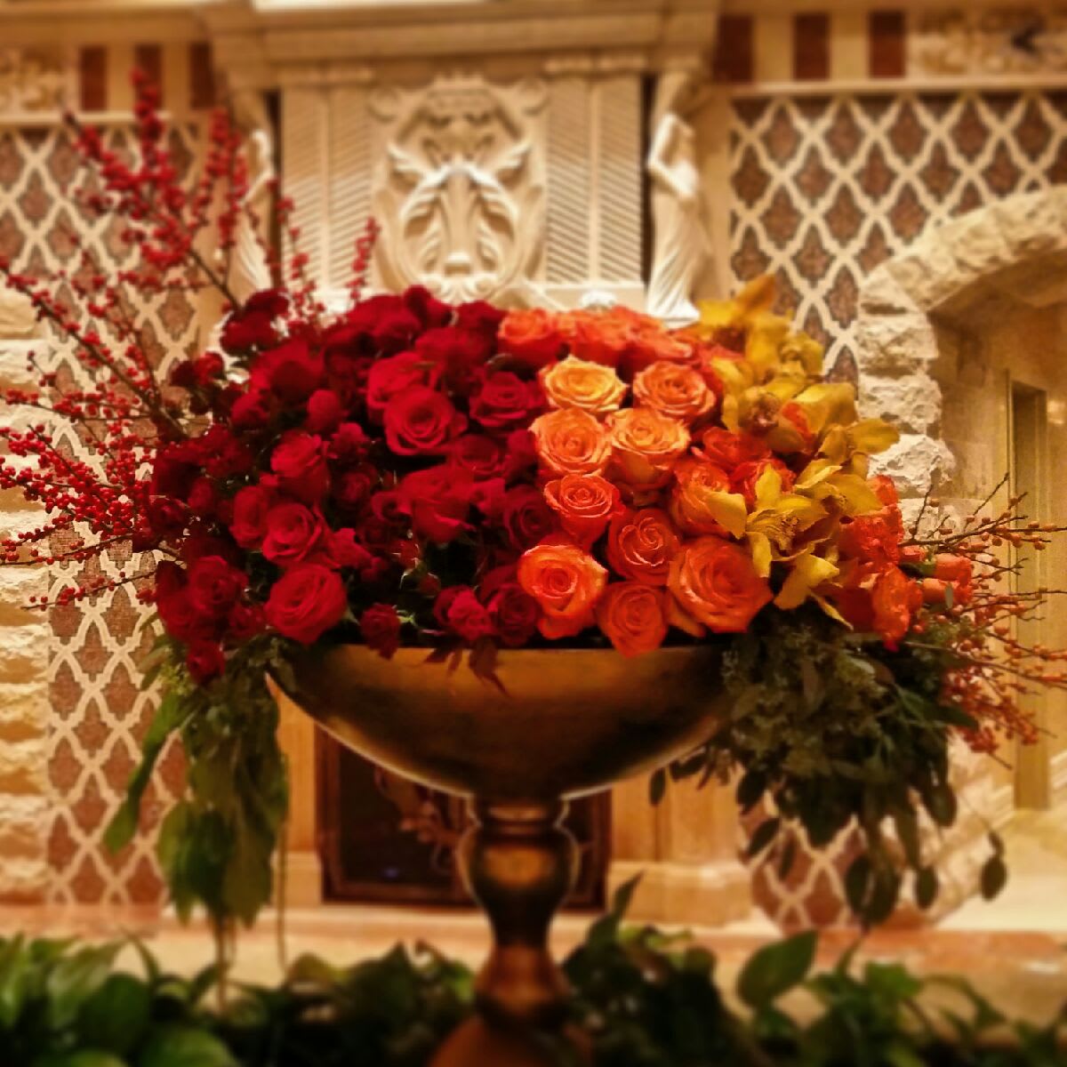 Hombre Romance Hombre Romance - A lush fade of red roses and ilex berries, roll into orange crush roses, and mellow out in a wave of yellow orchids and peach hypericum berries. It will definitely make a grand statement!