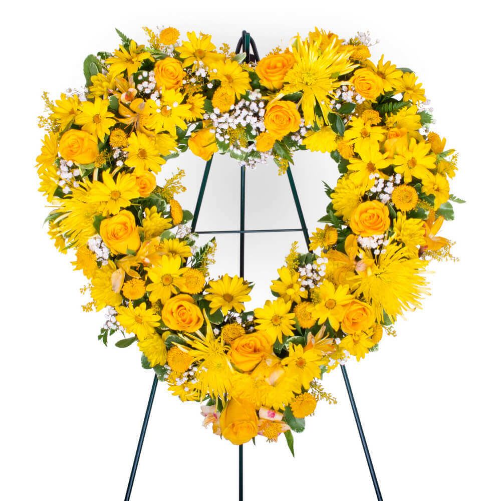 Yellow mixed heart On easel  - A mixed display of yellow bloom and tropical foliage displayed on a whimsical Hart on easel 