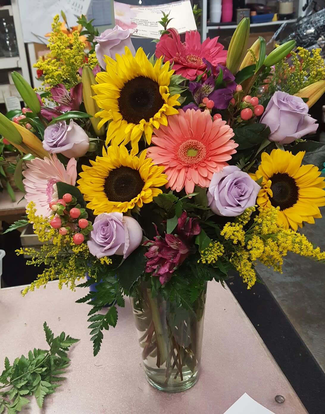 SUNFLOWER AMBIANCE - A VARIETY OF GREEN WITH GERBERAS, ROSES, LILIES AND POPS OF FILLER FLOWER TO GIVE THIS STUNNING ARRANGEMENT AN ARRAY OF TEXTURES.
