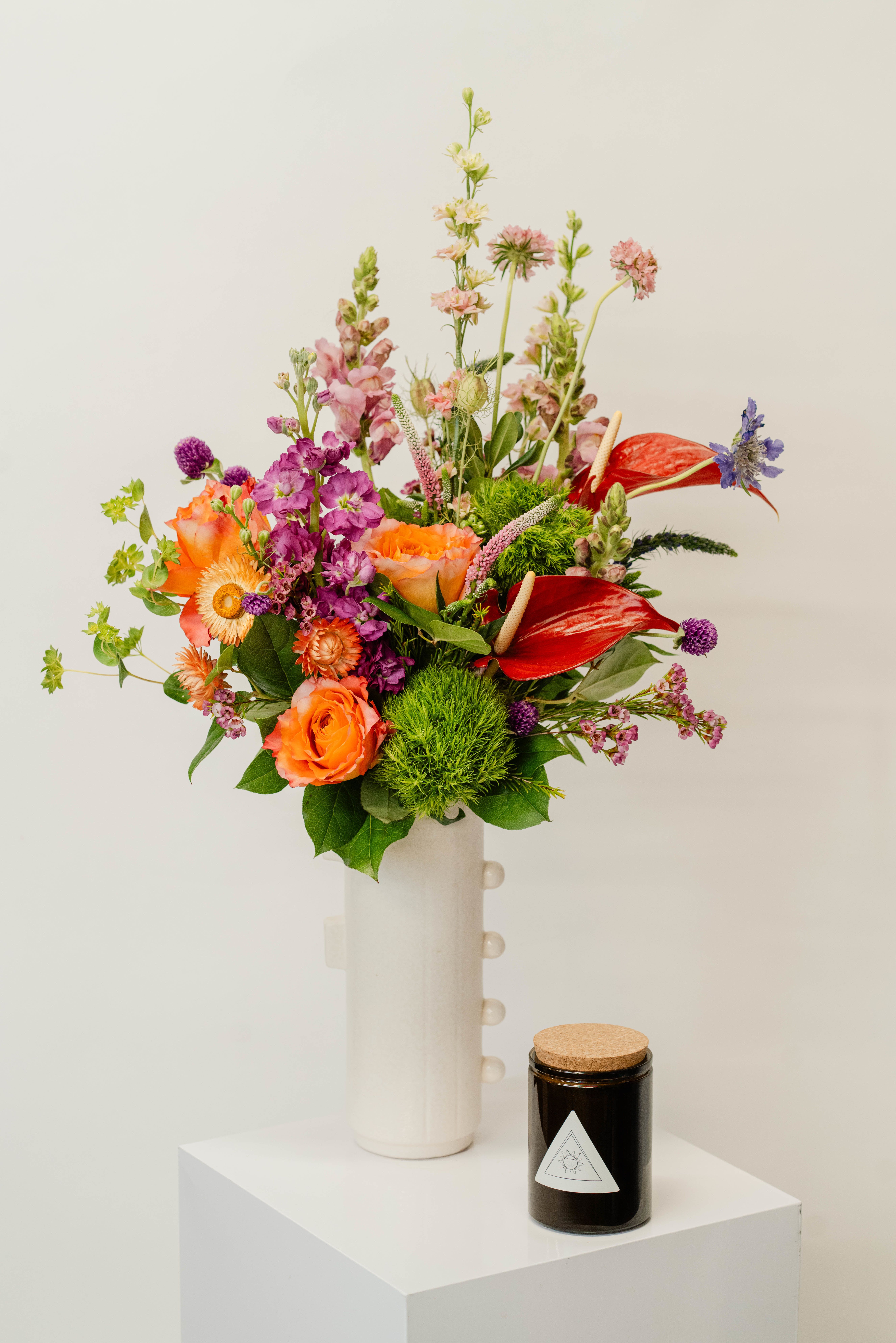 Deluxe Vase Design + Candle Bundle - Our deluxe curated vase design bundle features an opulent fresh floral arrangement paired with a premium handcrafted candle, designed to elevate any space with luxurious beauty and warmth.   Perfect for grand celebrations or gifting with exceptional flair, this bundle combines striking blooms and a rich ambiance to create an unforgettable impression.   