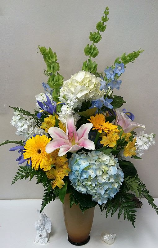 Springtacular Springtacular - This large spring bouquet is made all around with hydrangea, bells of ireland, stock, delphinium, gerbera daisies, iris and lilies in our signature amber vase. Spring mix may vary according to inventory.