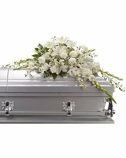 Bountiful Memories Casket Spray - A casket spray made of all white flowers and simple greenery is a simply stunning way to honor the deceased while bringing a quiet strength and serenity to those present. Gorgeous white oriental lilies, gladioli, carnations and more create a beautiful crescent shaped casket spray.