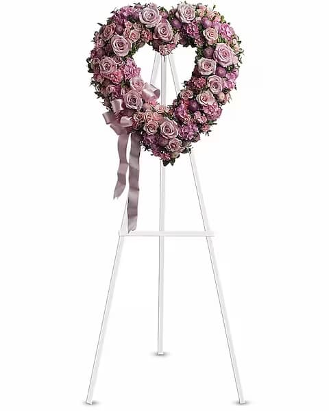 Rose Garden Heart Standing Spray - A tender and classic tribute to a precious life. Heartfelt emotions and sympathies find delicate expression here. Lovely flowers such as light pink roses, hydrangea and miniature carnations mix with lavender button spray chrysanthemums.  