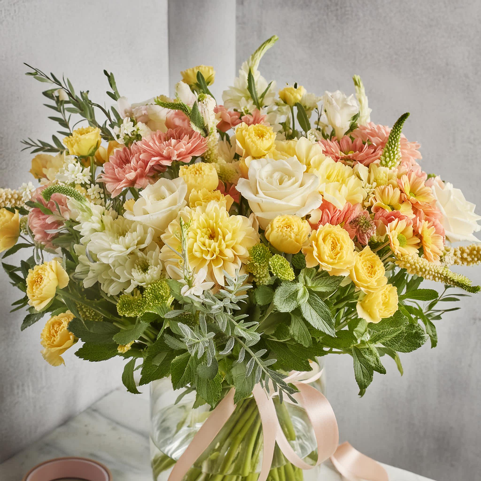"Canary Wharf Sunrise" "Canary Wharf Sunrise" - The "Canary Wharf Sunrise" bouquet is a vivid expression of a florist's Designer's Choice, where each flower is hand-selected for its contribution to the arrangement's overall warmth and radiance. Bursting with cheerful yellows and gentle pinks, this bouquet includes roses, chrysanthemums, and a mix of complementary florals, arranged with an eye for harmony and contrast. The Designer's Choice distinction ensures a personalized touch, with the florist's skill guiding the creation of a unique and memorable floral experience.