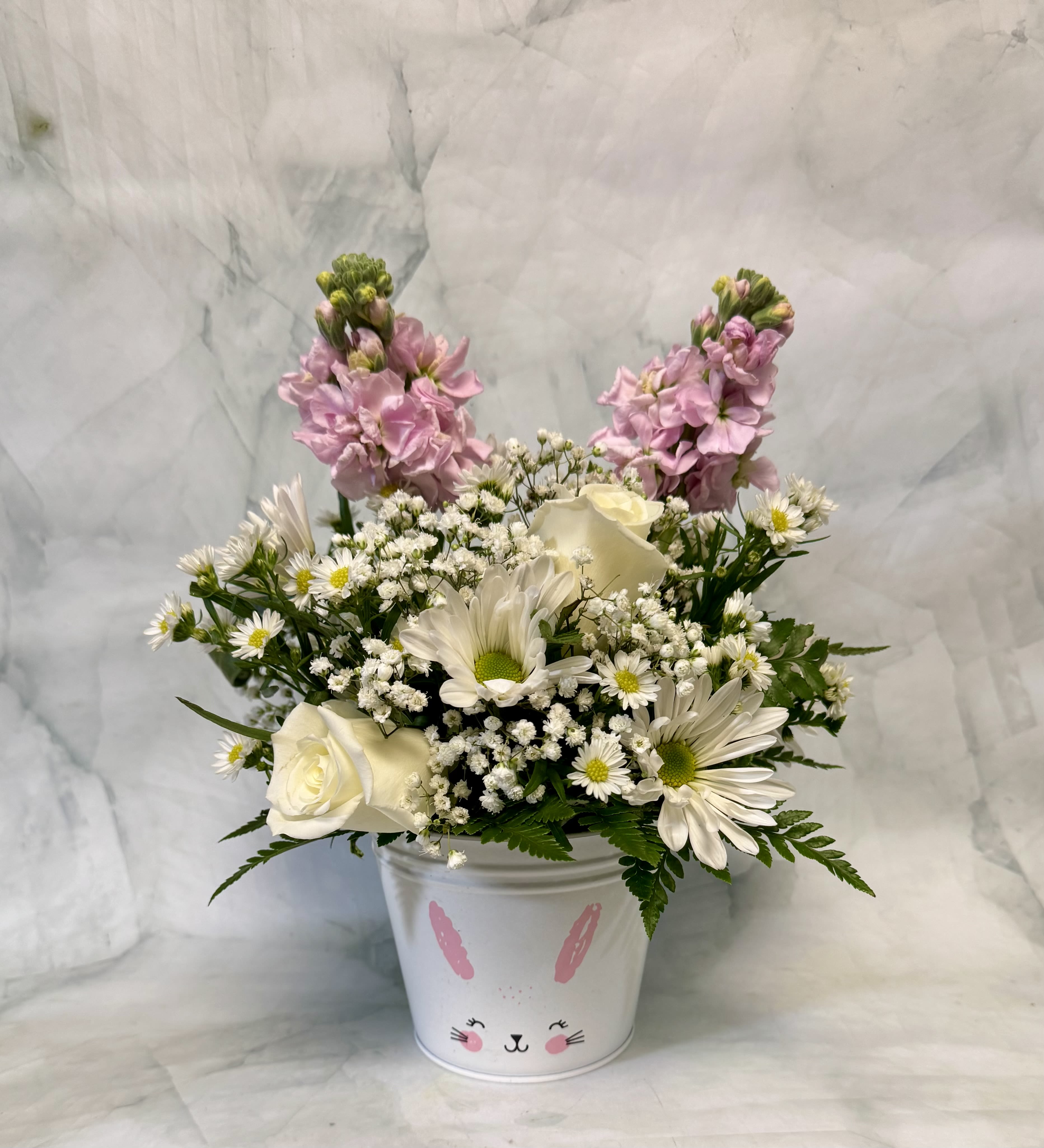 Easter Bunny Blooms  - This adorable arrangement is perfect for the Spring. It includes white roses, aster, Pom pons, and babies breath. There are two pink stock sticking up to resemble bunny ears. Get in the Easter spirit with this fun arrangement. 