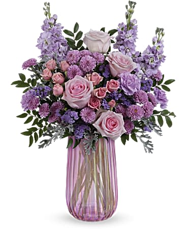 Iridescent Delight Bouquet  - What a delight! Overflowing with pink roses and lavender blooms, this decadent Mother's Day bouquet shines in an iridescent pink glass vase that Mom is sure to adore. Pink roses, pink spray roses, lavender carnations, lavender stock, lavender button spray chrysanthemums and lavender sinuata statice are arranged with huckleberry and silver lace dusty miller. This Mother's Day arrangement is delivered in Teleflora's Iridescent Delight vase.. Approximately 17 1/2&quot; W x 22 1/2&quot; H