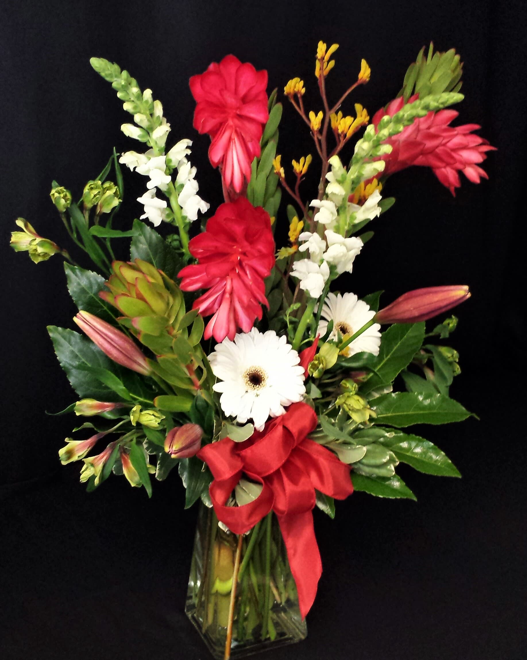 Ginger display in Rectangular Vase - Tall striking display of Bright, Vibrant flowers. Tropical and seasonal selection will be combined for a gorgeous mixed bouquet. Exact flowers and color may vary.  Please provide as much notice as possible so that we can get FRESH ginger (if seasonally available) and items as close as possible to photo. Otherwise another flower and other tropical flowers will need to be substituted.  