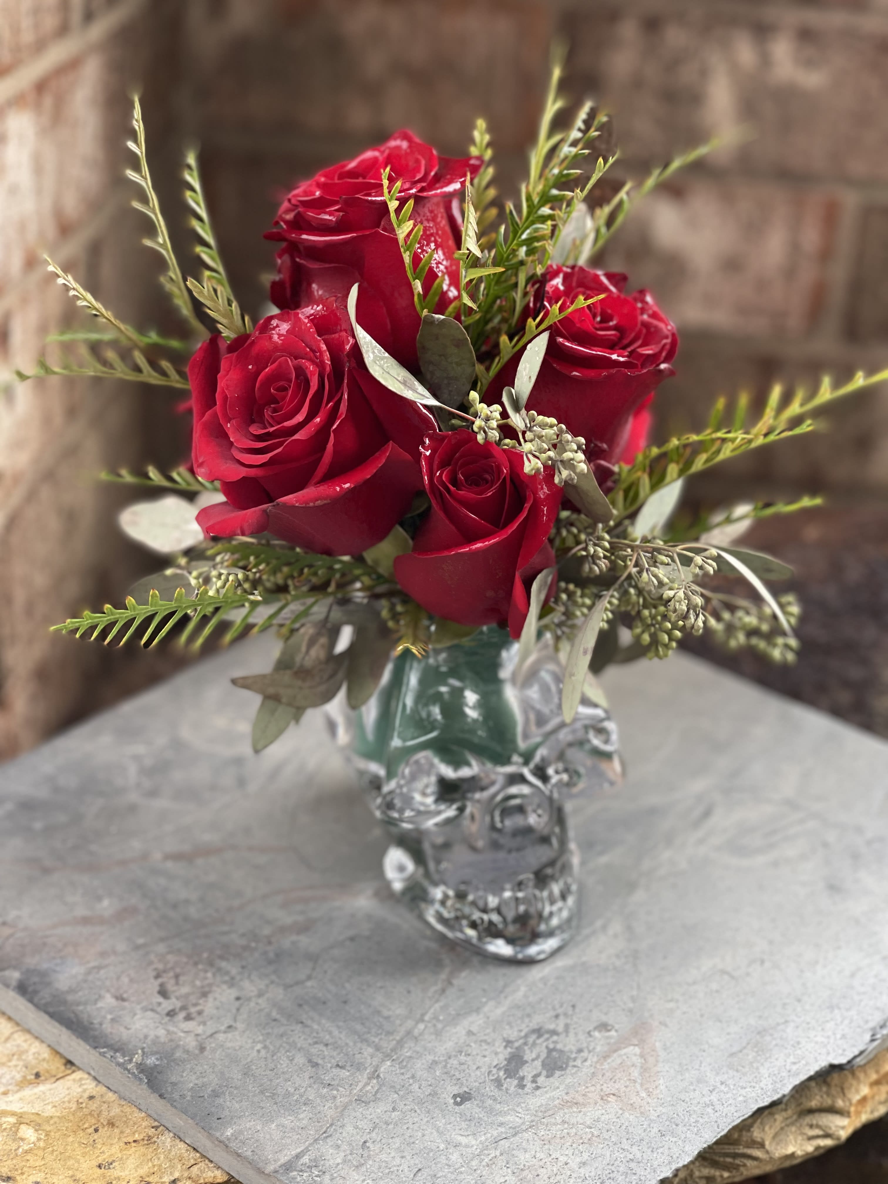 Skulls n' Roses - We take a clear glass skull and fill it with roses!! It's wicked!  Please note, this arrangement/vase is only available for local delivery. The area includes Bryan/College Station and surrounding areas (within 10 miles) only.