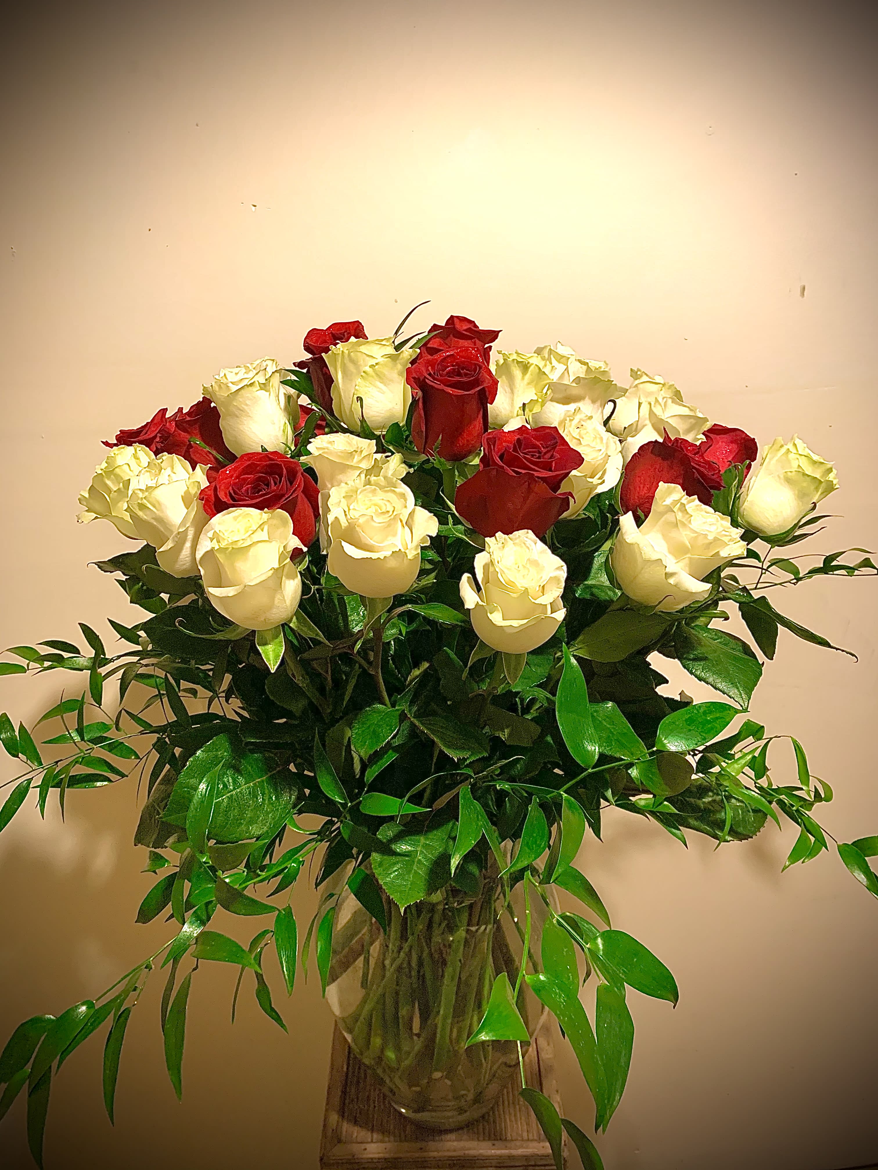 Unity Unity - Red and white roses together mean “unity “ . Perfect in every way. Three dozen roses arranged in a glass vase surrounded by lush greenery