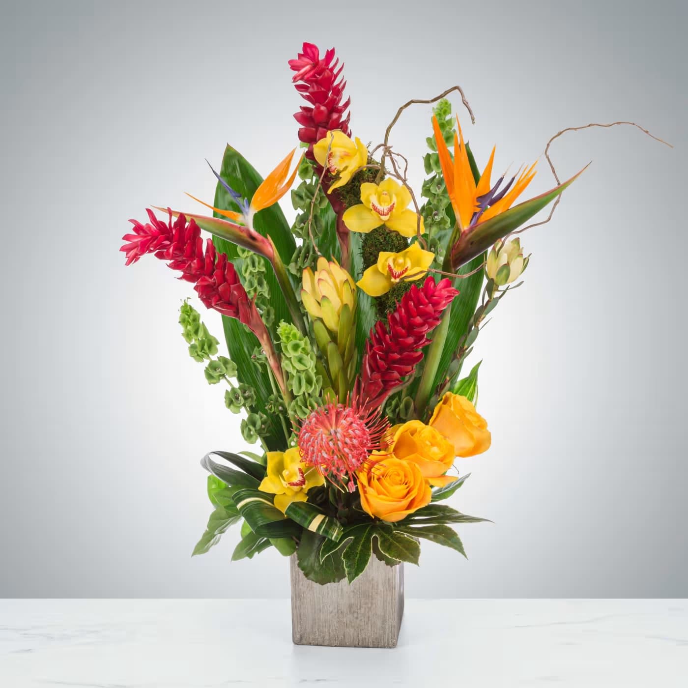 Tropic Like It's Hot by BloomNation™ Tropic Like It's Hot by BloomNation™ - Tropical plants come together in this one-sided tall standing arrangement. Featuring birds of paradise, ginger, and pincushion protea, this tropical selection would look lovely in any home. Approximate Dimensions: 22"D x 30"H