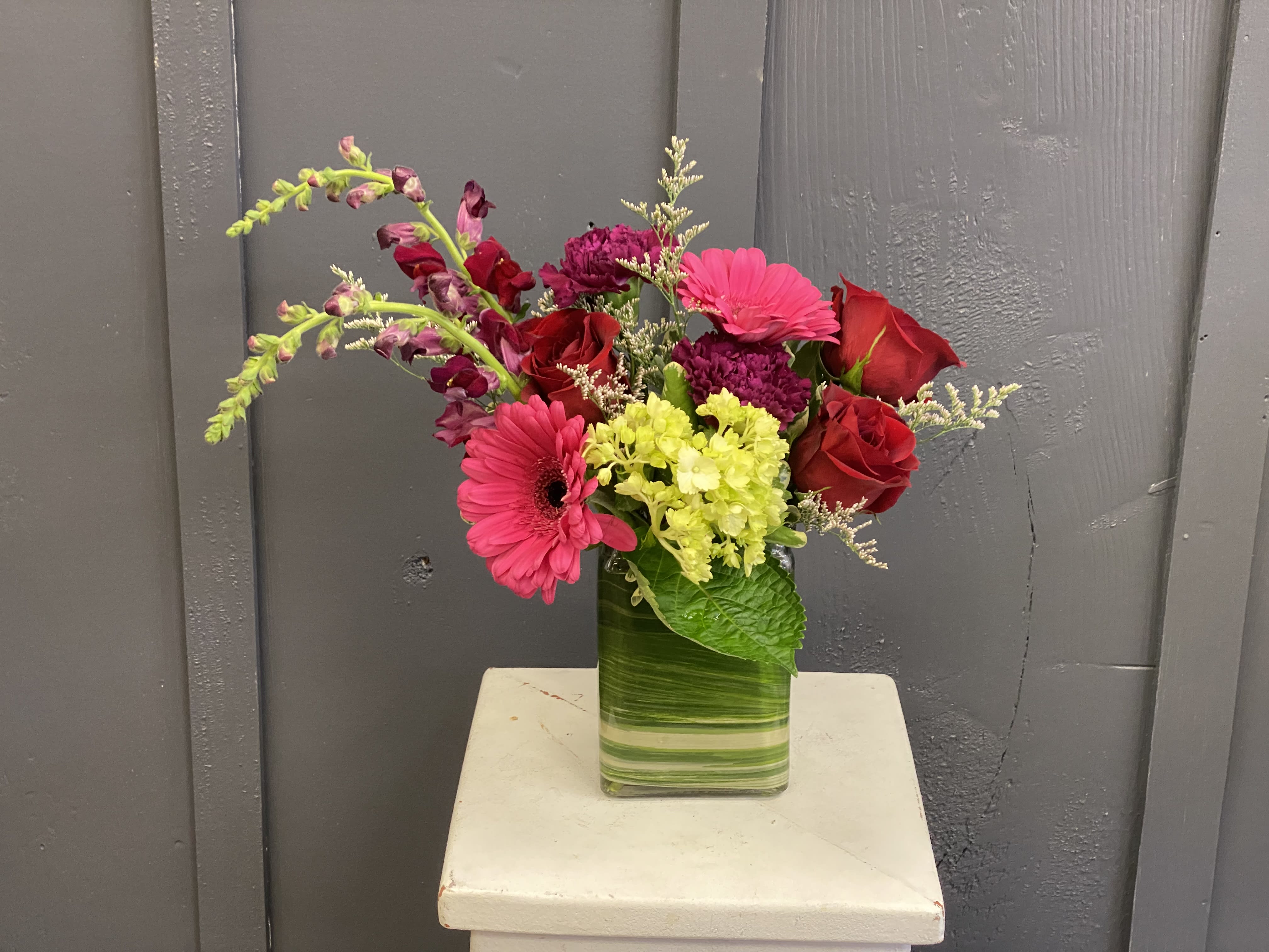 Bejeweled - A vibrant display of jewel toned florals in a leaf lined vase.