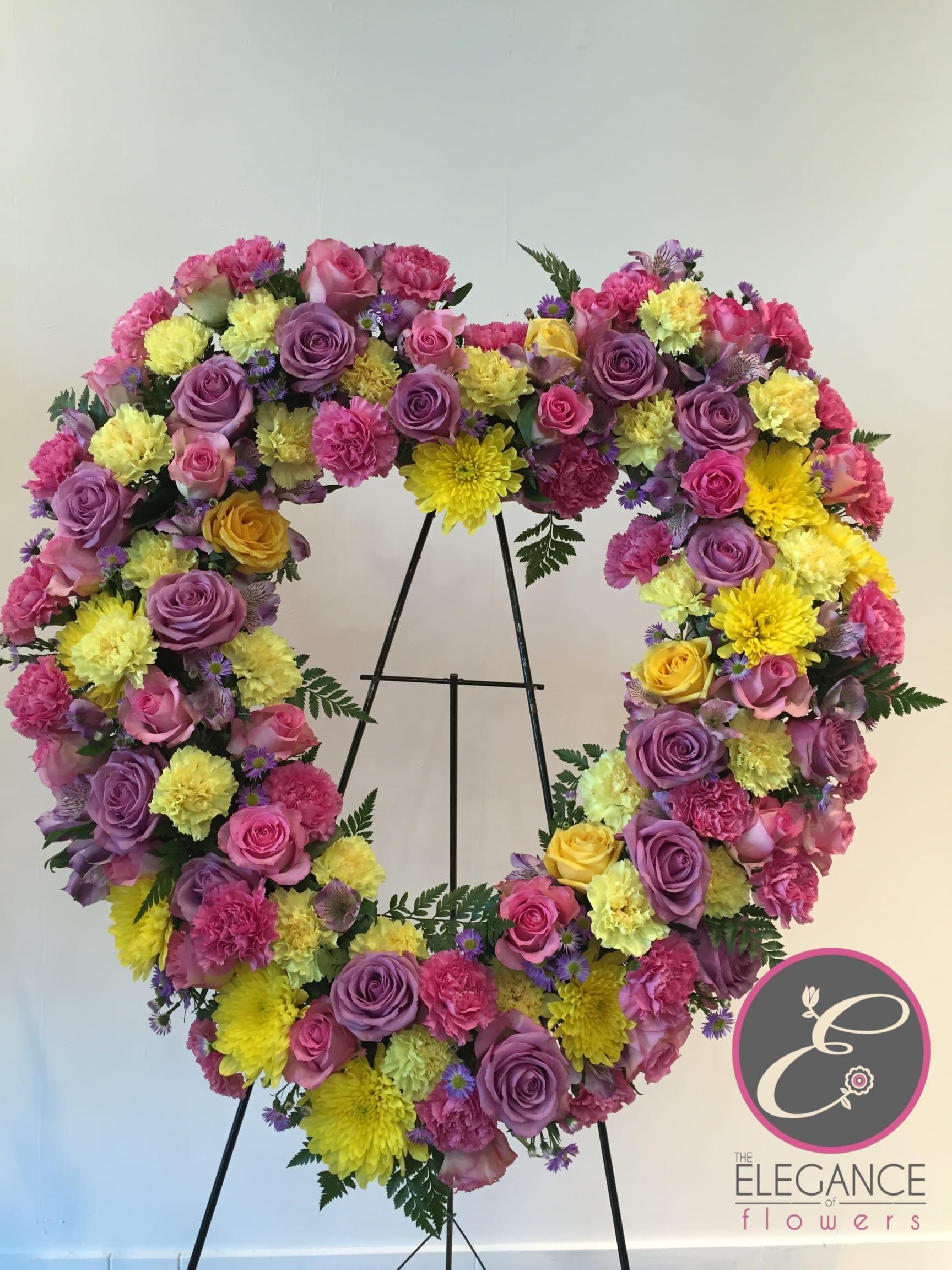Heart Wreath #9 Heart Wreath #9 - A standings flower arrangement for a funeral service is a heartfelt tribute designed to honor and celebrate the life of the deceased. These arrangements are typically displayed on an easel or stand, making them highly visible and a central part of the memorial decor.