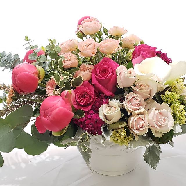 Pretty in pinks Mothers Day Ceramic vase  - This designers choice mix will be made in a white ceramic vase with the freshest in season blooms. In All shades of pink colors and hot pinks  Peonies, Roses. Spray Roses eucalyptus. and much more.   Peonies will be substituted if not available.  Picture Is premium size 