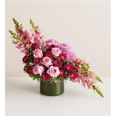 Charmingly Chic Charmingly Chic - This statement-making bouquet will dazzle even the most difficult to impress. Lavish blooms—roses! snapdragons! Matsumoto asters!—are arranged to create a dramatic linear silhouette. Please note that because this is a one-sided arrangement, no flowers are visible from the back. • One-sided arrangement of pink roses and snapdragons, hot-pink Matsumoto asters, lavender disbud mums, purple waxflowers and limoniums, and greenery • Because arrangement is one-sided, no flowers are displayed on the back • Artistically designed in a clear glass cylinder vase wrapped in ti leaf ribbon