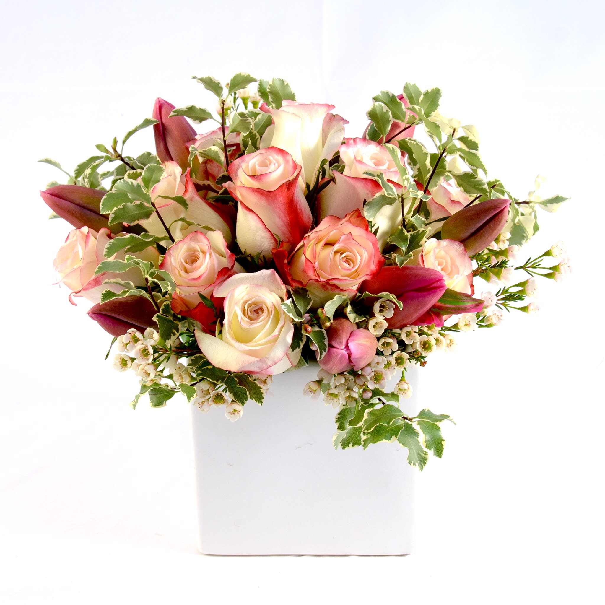 Berthe - A gathering arrangement of peachy roses and lavender tulips with lightly greens. Modern twist with classic colors in low-compact, white vase. (Approx. size 8&quot;w x 8&quot;h x 8&quot;d)