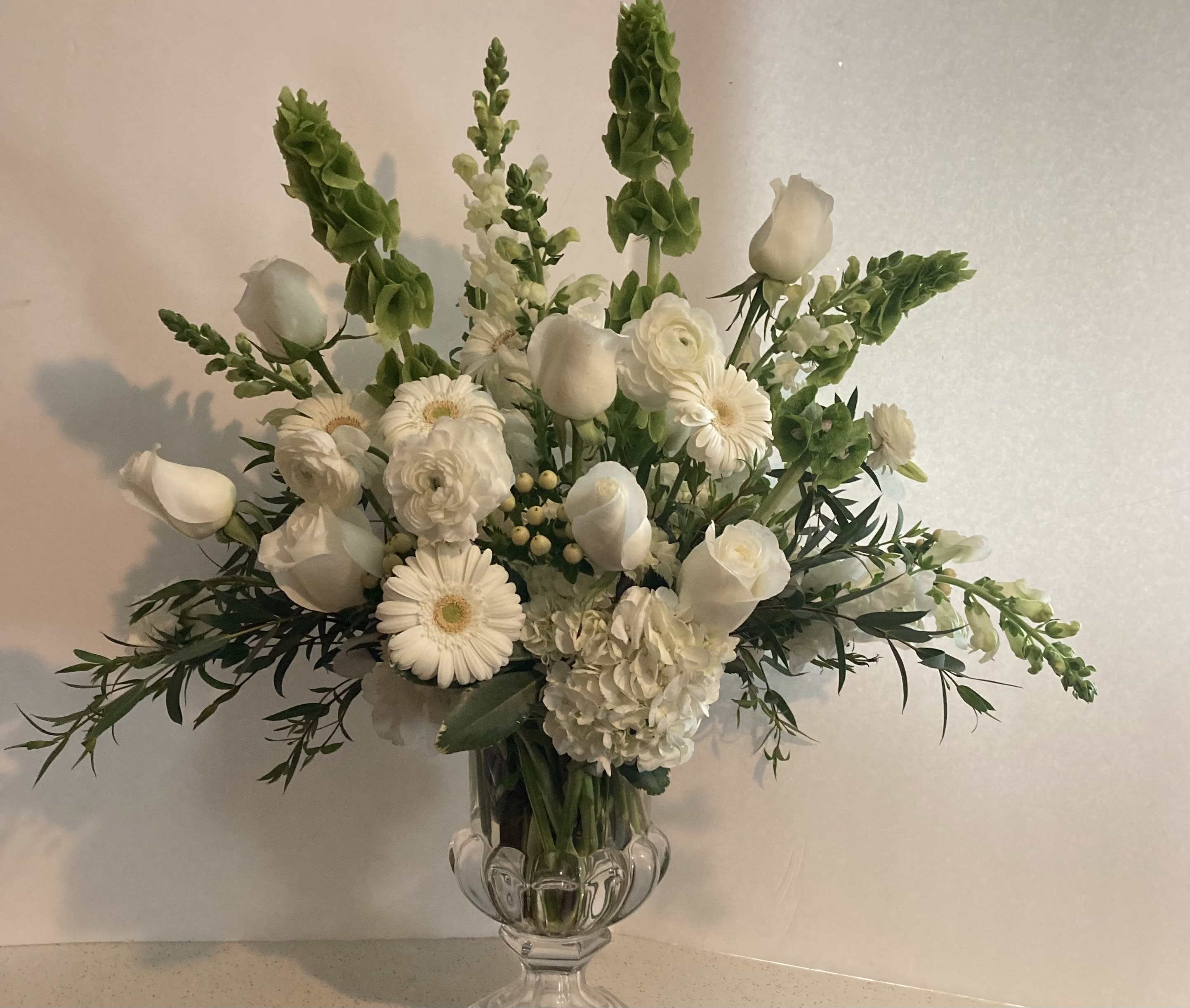 Quiet Times - A bouquet in white with a touch of green. Gerberas, bells of Ireland, snapdragons, hydrangea, and roses.
