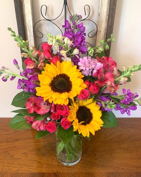 Happy Heart - A mixed fresh cut consisting of Sunflowers, Fuchsia Alstromeria, Purple Stock, Hot Pink Spray Roses, Orange Snapdragons, Pink Larkspur, and Lavender Scabiosa.