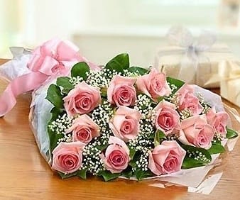 Dozen Pink Roses Wrapped - A dozen pink roses with greens and filler flower wrapped in a cellophane wrap with a bow. 