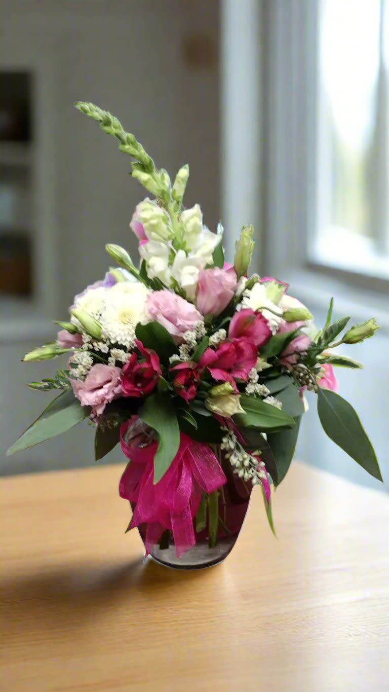 Pink Petal Serenade - Pink Petal Serenade: Experience the symphony of colors with Petal Serenade, a stunning floral arrangement featuring various shades of pink and white snapdragons, alstromeria, and lisianthus. Enhanced with vibrant greens and filler flowers, this design is a celebration of nature's beauty, ideal for brightening up any room.  When you request custom designs, we will create them to closely resemble the picture. Keep in mind that each design is unique and made just for you. Due to the nature of flowers, color substitutions may be required. Prices and availability of seasonal flowers can also differ.