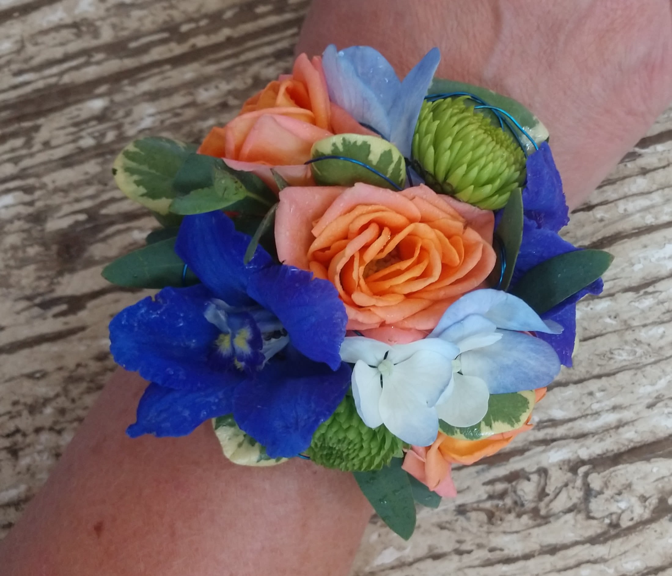 Emotions Emotions - Complimentary to each other the orange roses and blue delphinium and hydrangea blooms accented with lime green button mums make this a FUN cuff.
