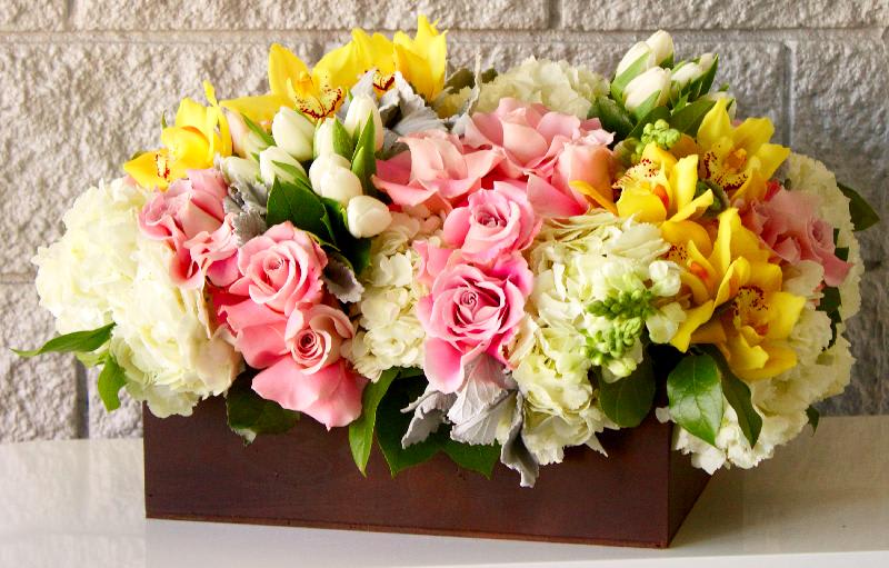 Pure Cheer Pure Cheer - A long and low container overflowing with gorgeous pink roses, yellow orchids, tulips, and hydrangeas to make someone's day.