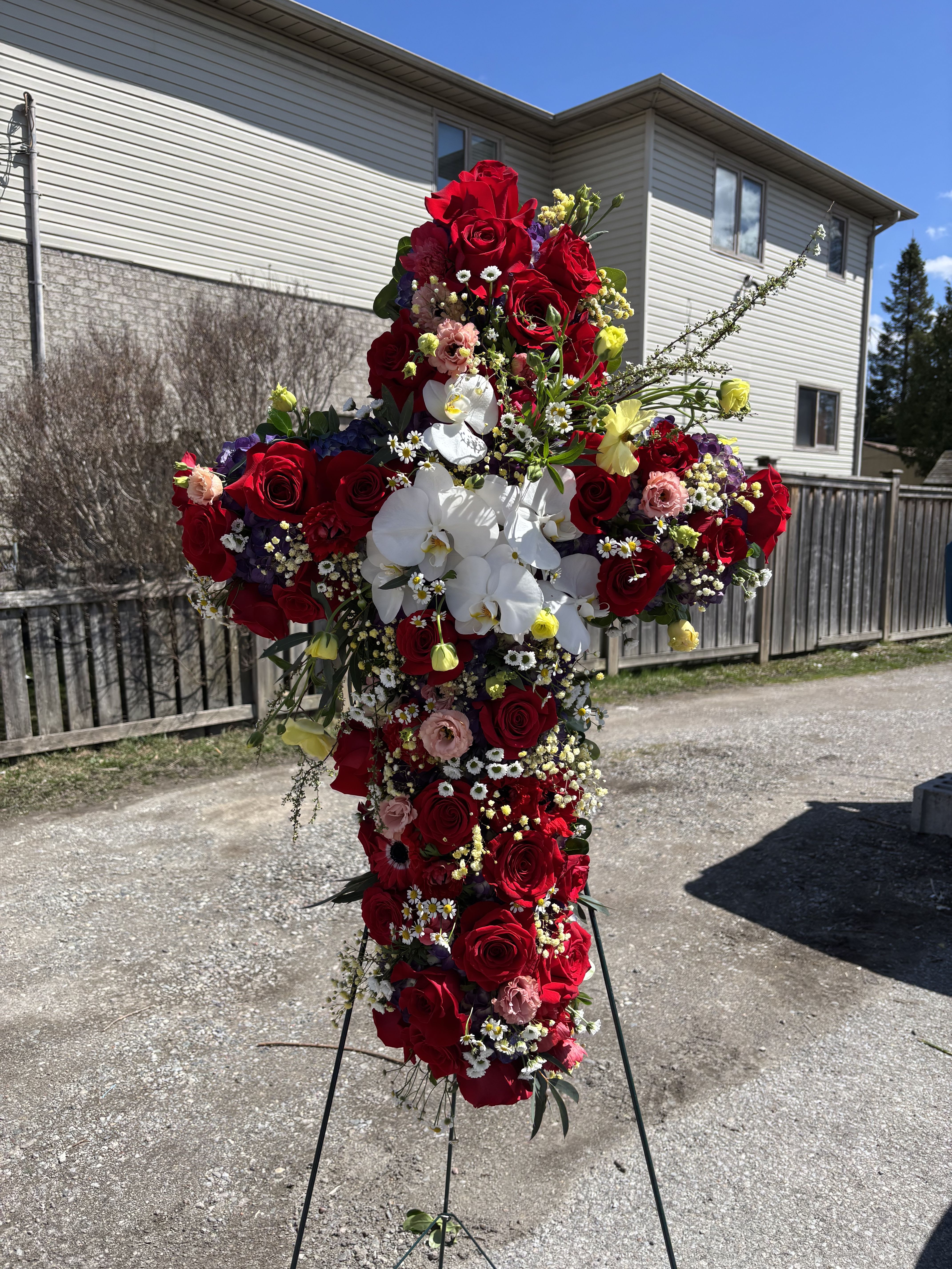 Eternal Grace Cross Eternal Grace Cross - A heartfelt funeral tribute featuring vibrant red roses and delicate white blooms, elegantly arranged in the shape of a cross to symbolize faith, love, and remembrance.