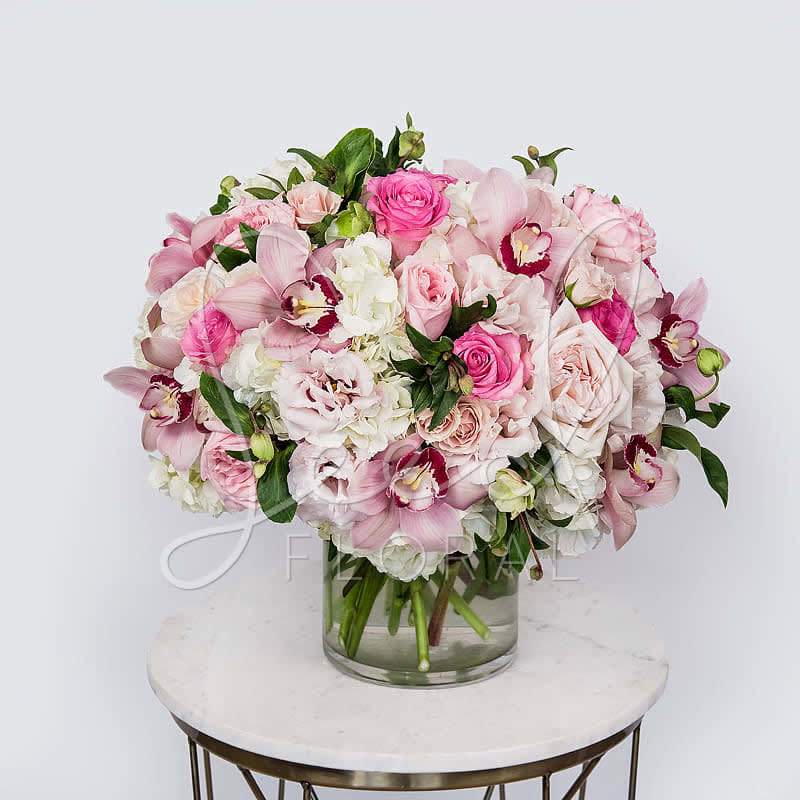 Pink Glamour  - Our sweet version of the 'White Glamour' is designed of chic pink blooms including hydrangea, roses, garden roses, and cymbidium orchids is the ultimately luxurious yet delicate arrangement in a clear glass vase.