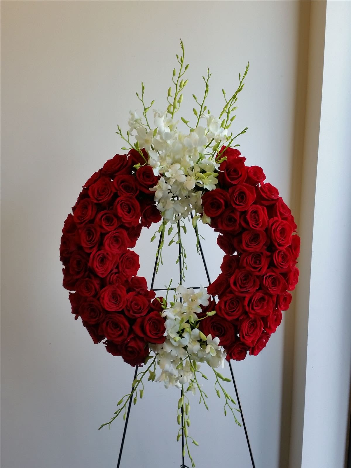 Red Wreath  - Open, wreath- shaped arrangement designed with red roses and orchids. Appropriate for the funeral home.