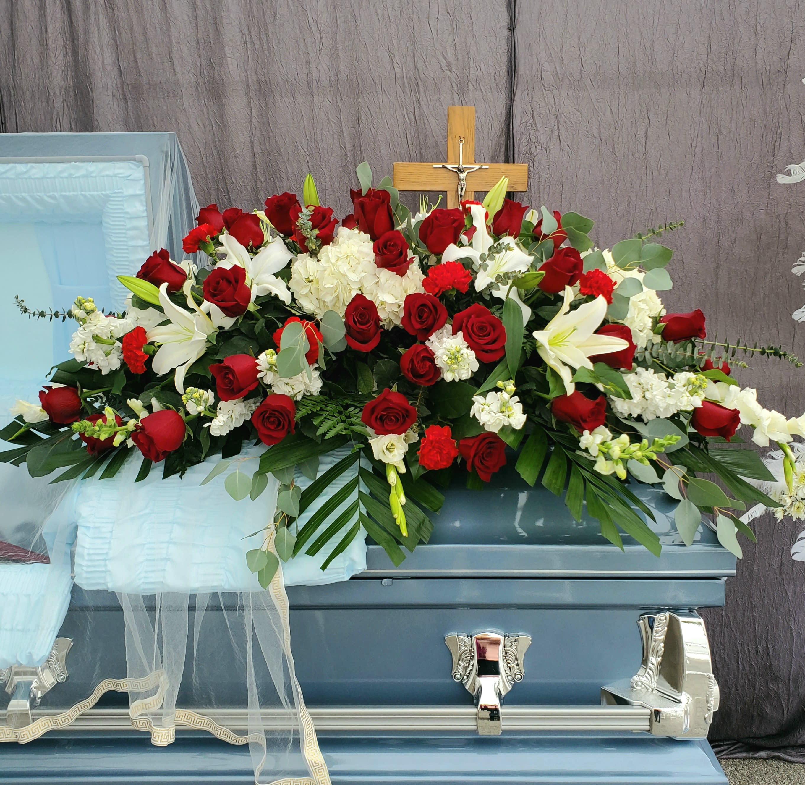 Forever Loved Casket Spray - 4 dozen Ecuadorian roses surrounded by white lilies, white hydrangea, and several other white blooms and foliage that give this large casket spray a beautiful plush  look. This large casket measures approximately 3.5-4 ft in length.