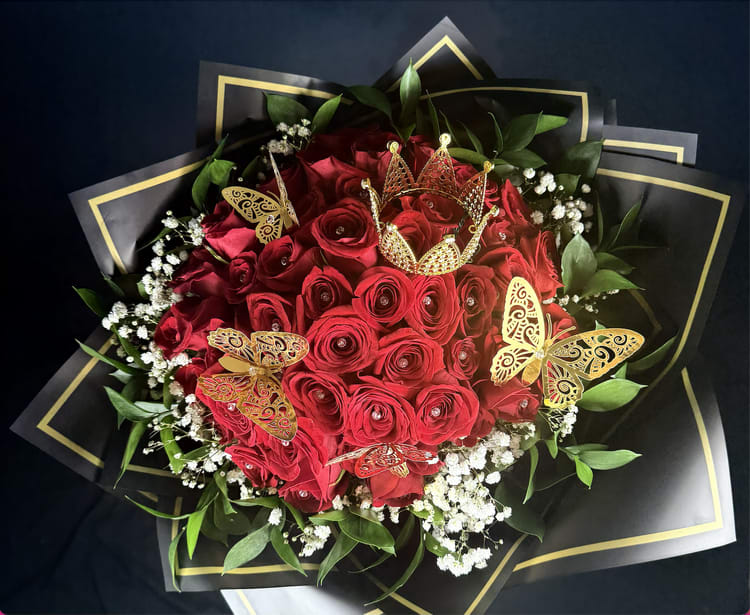 48-Red Roses Bouchon Bouquet - XL Bouchon bouquet  For those who wish to express their love in the most unforgettable way, the 48-Rose Bouchon Bouquet is the epitome of elegance and grandeur. This extraordinary arrangement boasts an impressive 48 luxurious red roses, each one hand-selected for its stunning beauty and perfect form. Surrounded by soft baby’s breath and every rose is embellished with sparkling diamond-shaped stones. This bouquet is adorned with delicate gold metallic crown and gold butterflies, creating a breathtaking display that radiates romance and opulence. Tied together with an elegant black ribbon, this bouquet is not just a gift; it's an experience—one that will leave your special someone in awe and filled with joy.  When words alone aren’t enough, the 48-Rose Bouchon Bouquet speaks volumes, making it the perfect gesture for those who want to show their love in the grandest and most impressive way possible. This bouquet is for those who believe that love should be celebrated with passion, beauty, and an unforgettable statement.  It also comes with a small message card from the sender, allowing you to personalize your gesture with a heartfelt note.