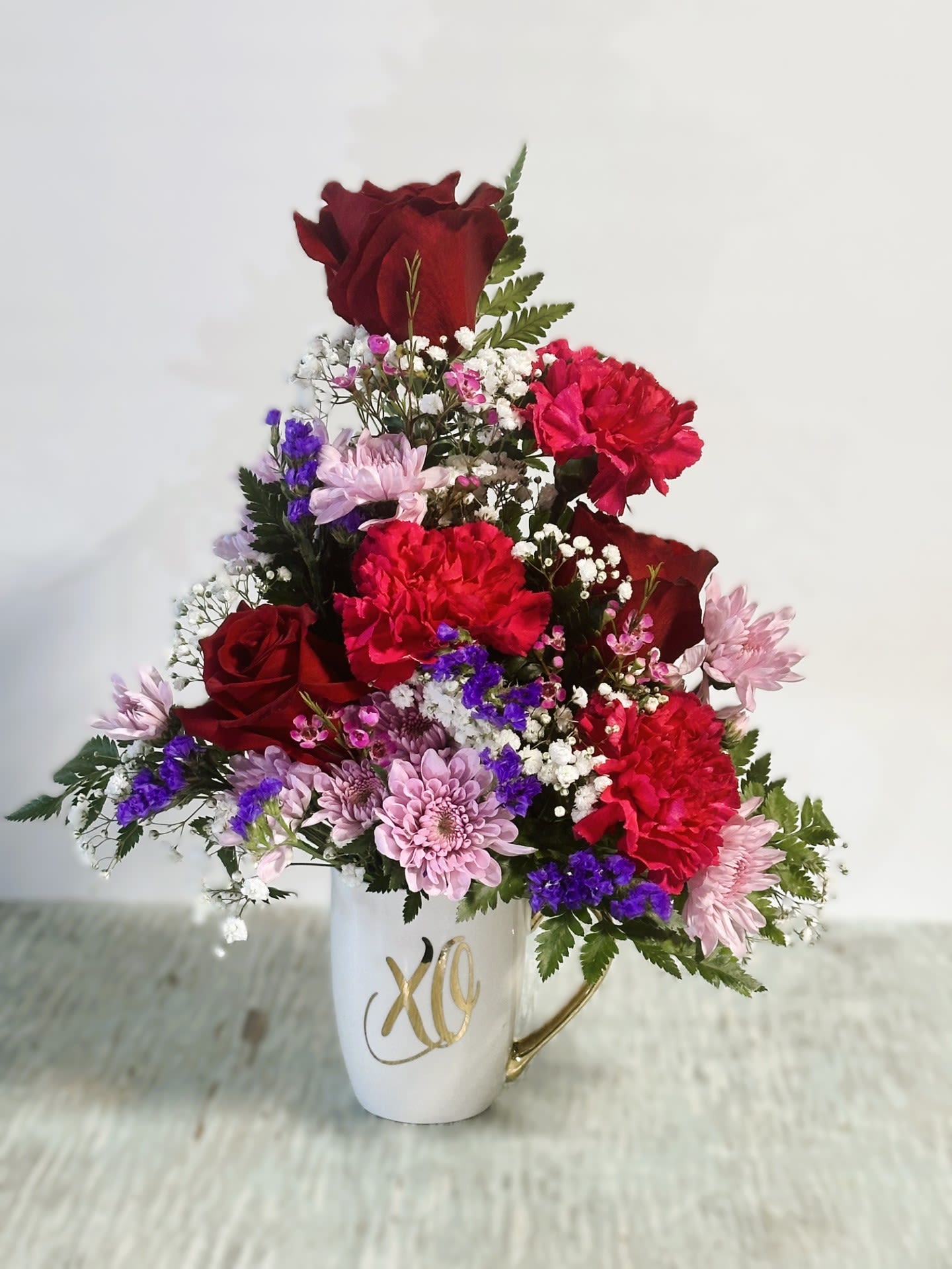 Love &amp; Romance Cup #3 - Arrangement of red roses, magenta carnations, lavender cushion poms, purple statice, babies breath &amp; leather fern arranged in a ceramic mug(12oz.) that reads &quot;XO&quot; in metallic gold print.
