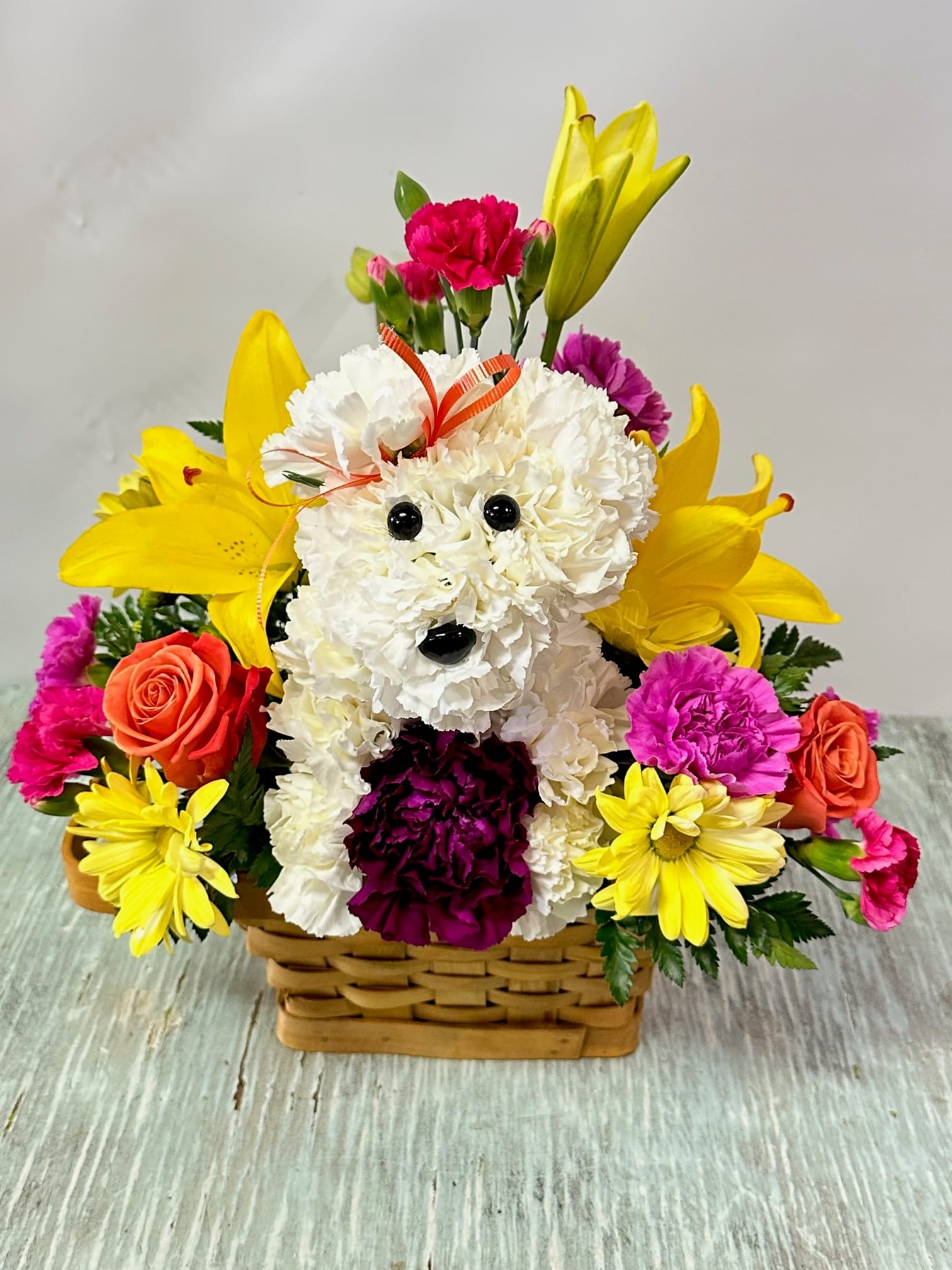 Get Well #5 - Arrangement of fresh cut flowers designed in a brown rectangular basket. Includes puppy sculpted out of fresh cut white carnations. Colors can be modified depending on availability.