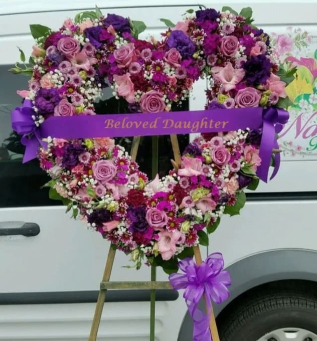 Sympathy Open Heart #49 - Standing open heart made of purple, lavender and pink fresh cut flowers. Colors can be modified depending on availability. Designed on an easel that is included with the arrangement and does NOT need to be returned. Banner is included with arrangement. Please specify what is to be printed on banner upon check out under &quot;FLORIST INSTRUCTIONS&quot;. LIMITED TO 5 WORDS ON BANNER.