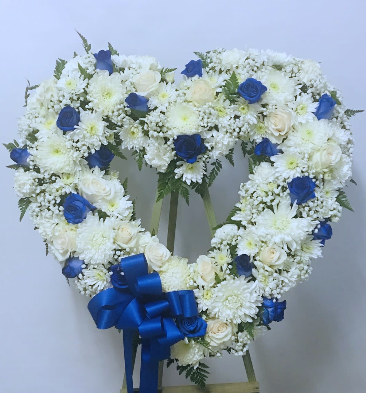 Sympathy Open Heart #52 Sympathy Open Heart #52 - Standing open heart made of white and blue fresh cut flowers. Please be advised that roses do NOT naturally come in blue. They are either dyed of spray painted with a special paint that will not harm the roses. Colors can be modified depending on availability. Designed on an easel that is included with the arrangement and does NOT need to be returned.