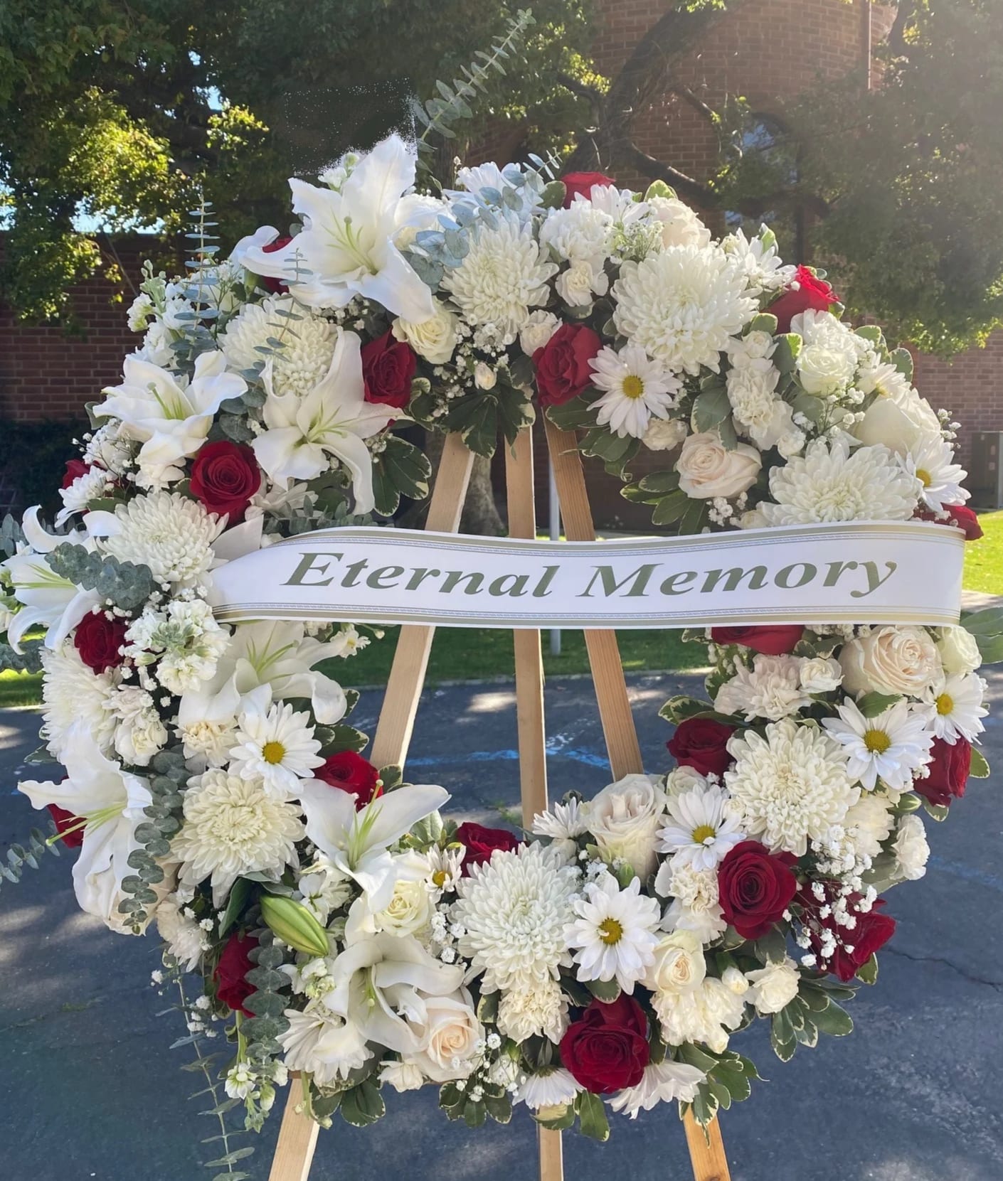 Sympathy Wreath #45 - Standing wreath made of white and red fresh cut flowers. Colors can be modified depending on availability. Designed on an easel that is included with the arrangement and does NOT need to be returned. Banner is included with arrangement. Please specify what is to be printed on banner upon check out under &quot;FLORIST INSTRUCTIONS&quot;. LIMITED TO 5 WORDS ON BANNER.