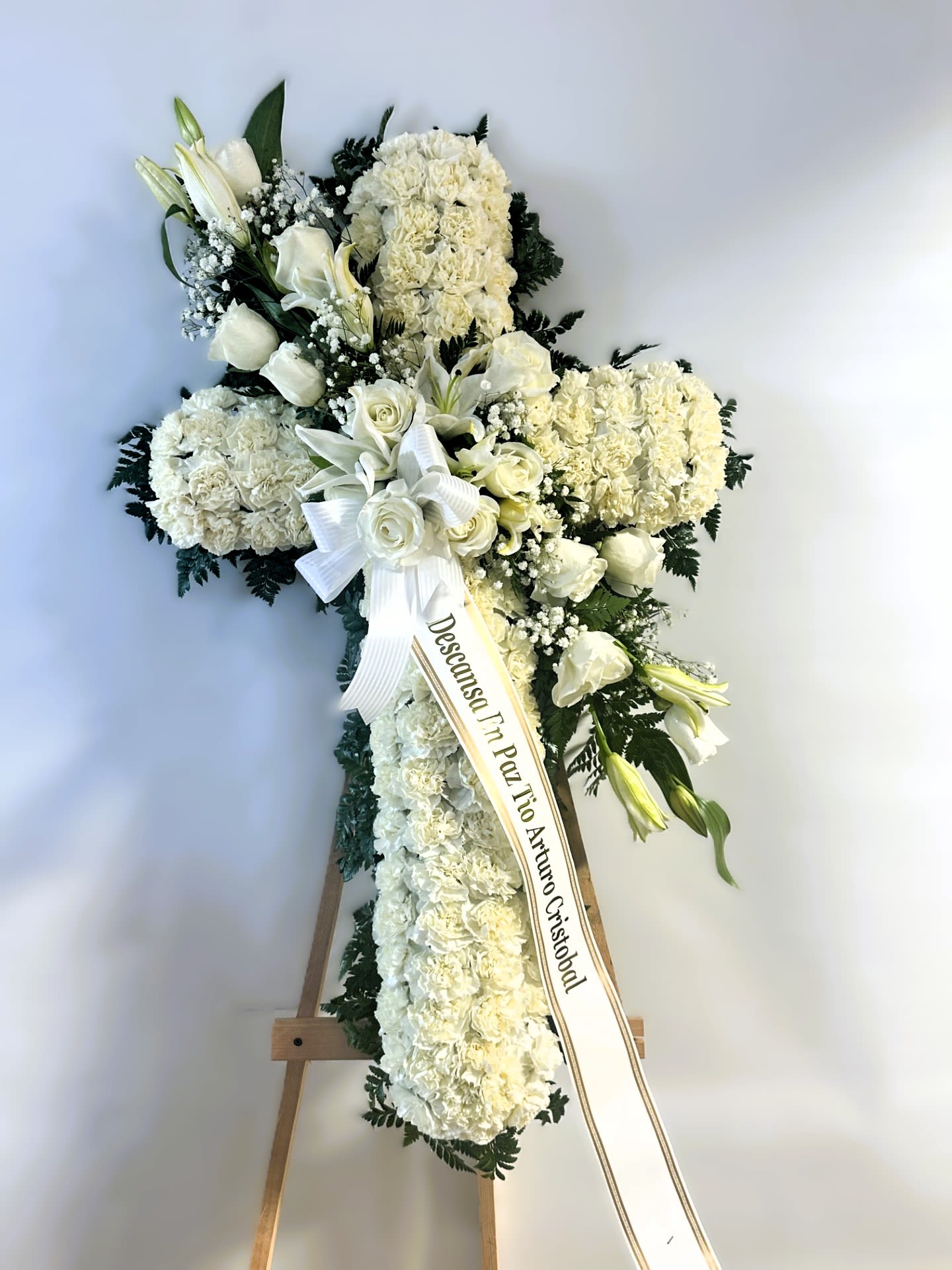 Sympathy Cross #43 - All white standing cross with an all white cluster of fresh cut flowers. Colors can be modified depending on availability. Designed on an easel that is included with the arrangement and does NOT need to be returned. Banner is included with arrangement. Please specify what is to be printed on banner upon check out under &quot;FLORIST INSTRUCTIONS&quot;. LIMITED TO 5 WORDS ON BANNER.