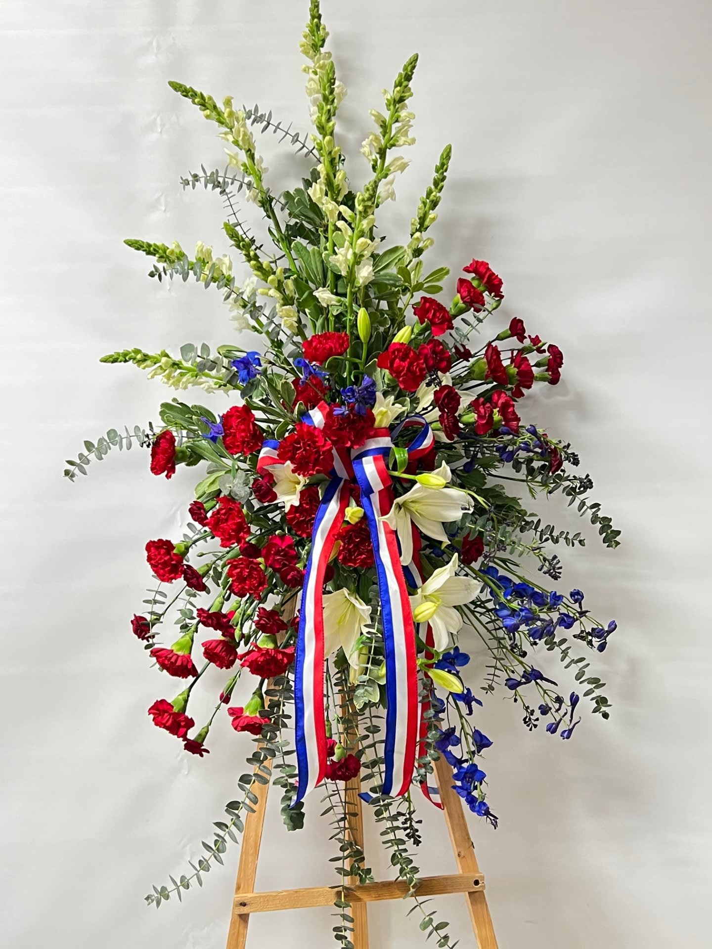 Sympathy Standing Spray #34 Sympathy Standing Spray #34 - Standing spray of fresh cut flowers. Designed on an easel which is included with the arrangement and does NOT need to be returned. Embellished with a red, white and blue bow.