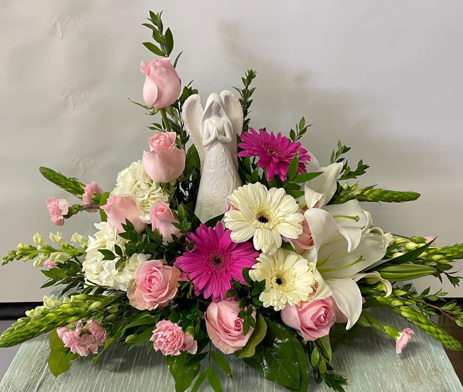 Sympathy #22 - An arrangement of fresh cut flowers. Arrangement includes an all white angel statue. Angel statue will be substituted for a similar angel depending on availability. Colors can be modified depending on availability.