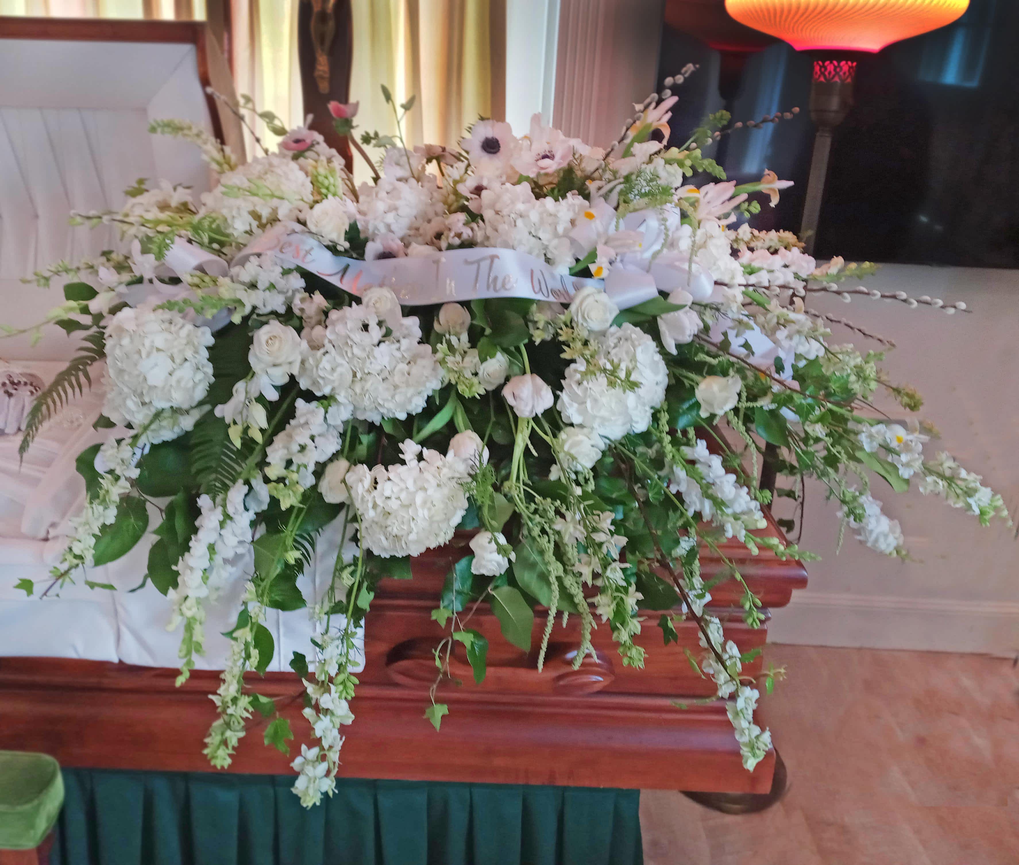 All White Casket Spray All White Casket Spray - Show purity of love with a mix of all-white flowers that’s as gentle and pure as a cloud. Accented with a mix of greenery, fragrant white flowers create a lovely and traditional casket spray.