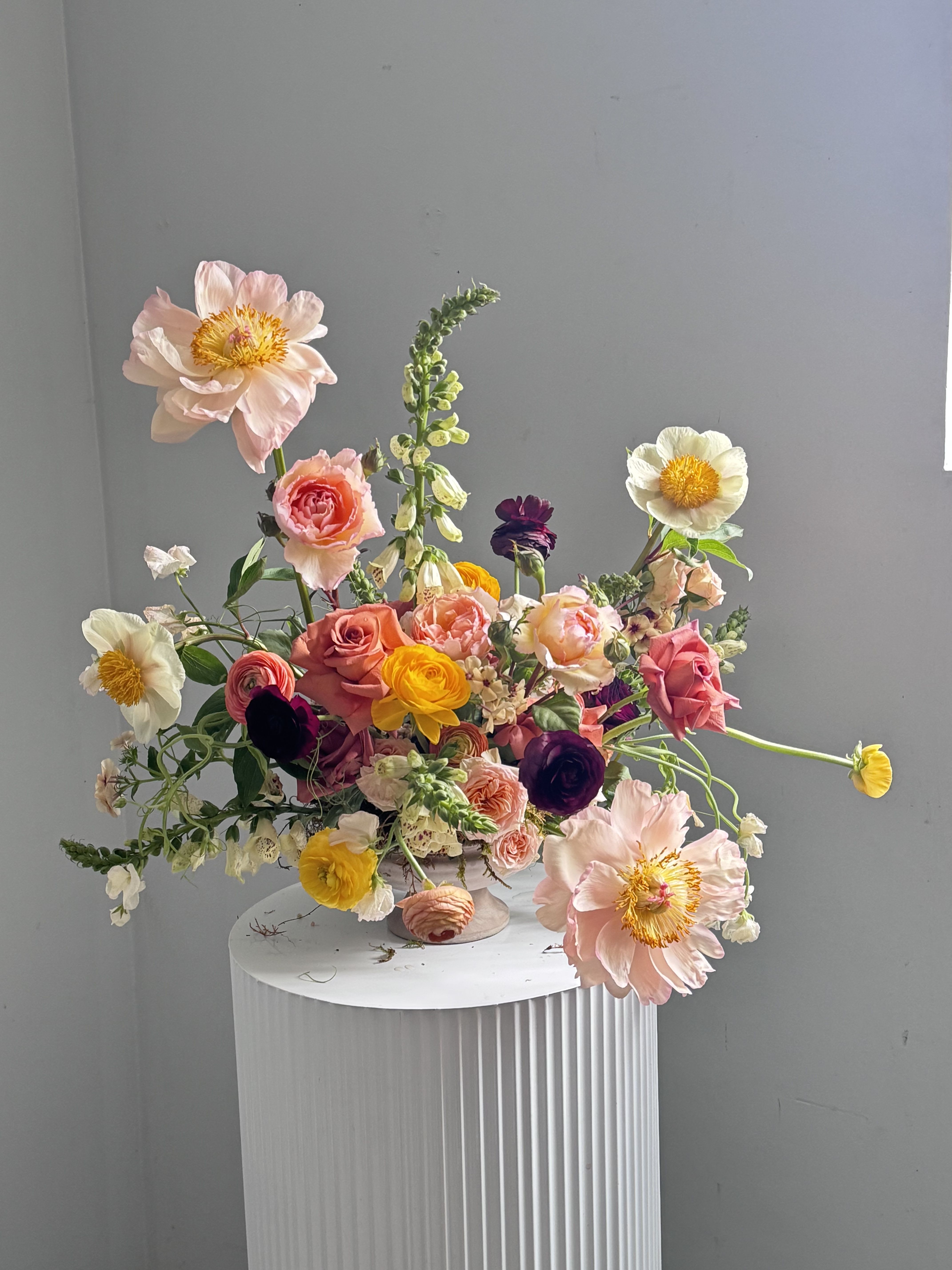 Honeyed Bloom Honeyed Bloom - Honeyed Bloom - A delicate dance of warmth and grace, Honeyed Bloom is a soft, sun-kissed bouquet that captures the gentle beauty of a golden morning. Blush peach-toned garden roses and burgundy ranunculus mingle with buttery yellow peonies, creating a palette as sweet and inviting as honey on warm toast.