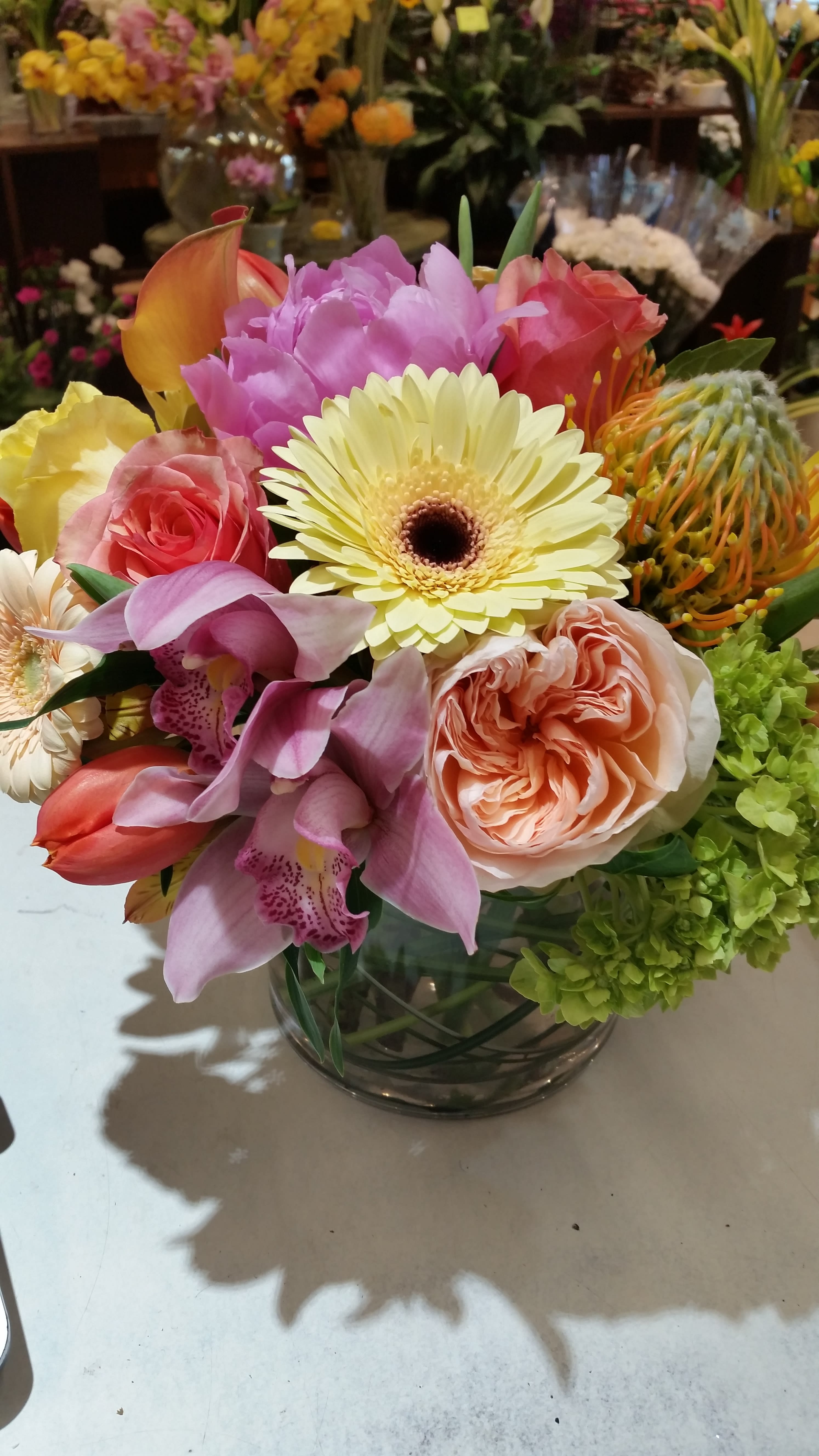 Southern Comfort Southern Comfort - This lovely cylinder arrangement makes great use of mid-tone pastel colors. We could just picture these flowers on a table in a seaside beach house. Rose-colored cymbidium orchids work well with peach Garden roses, pale yellow Gerbera daisies and various shades of premium roses. We think this piece is practical as well, making a great gift for birthday, thank-you or get well.