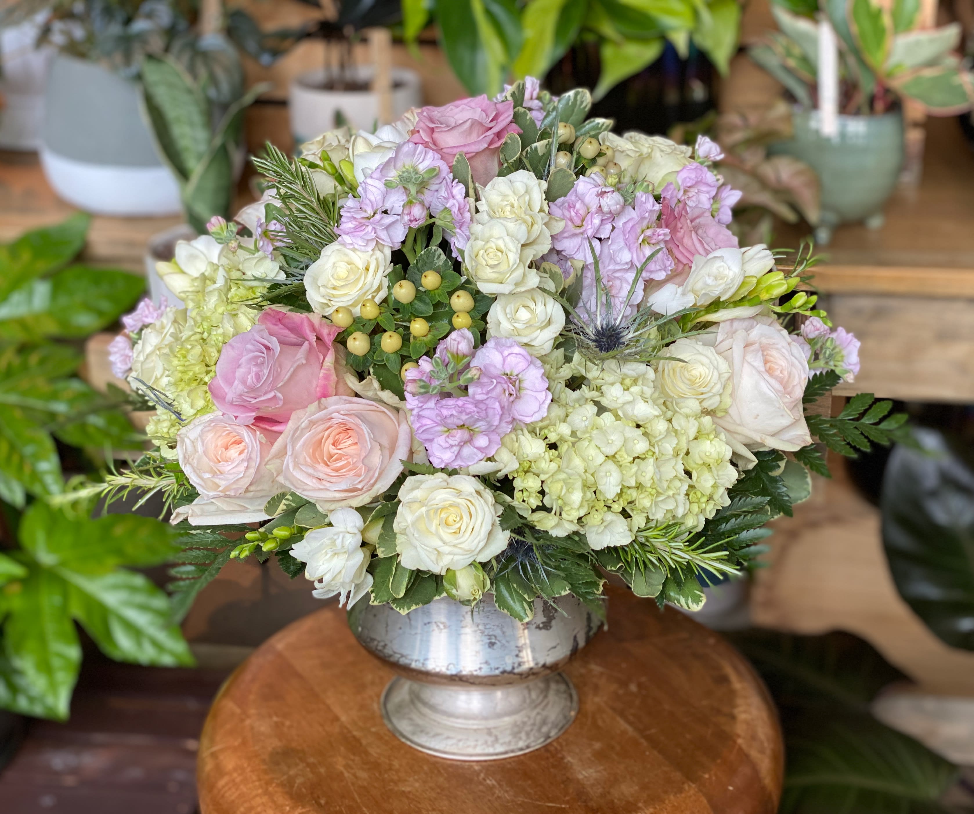 The Emmy by Simply Fresh Flowers - An elegant all sided display of garden roses, roses, stock flower, hydrangea, hypericum berries, thistle and other seasonal accent blooms designed in a silver, mottled urn. Simply an exquisite arrangement, suitable for any occasion!