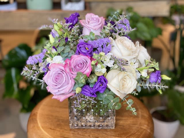 The Violet by Simply Fresh Flowers The Violet by Simply Fresh Flowers - The Violet is an all sided design, arranged in a textured cubed vessel, incorporating lavender & white roses, stock, freesia, eucalyptus & other coordinating seasonal blooms. A simply soft & sweet sentiment for a very special someone!